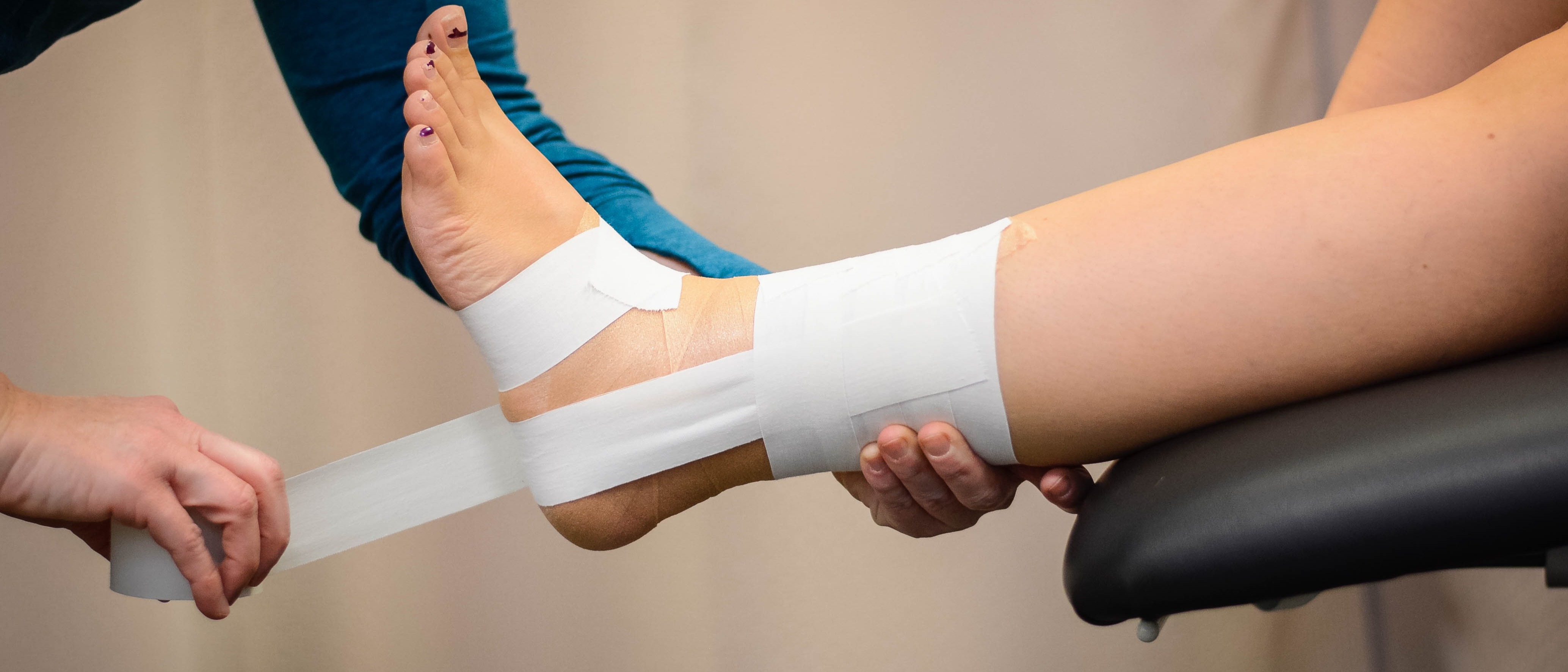 Hands and legs supported with white bandages during physical therapy stretching session.